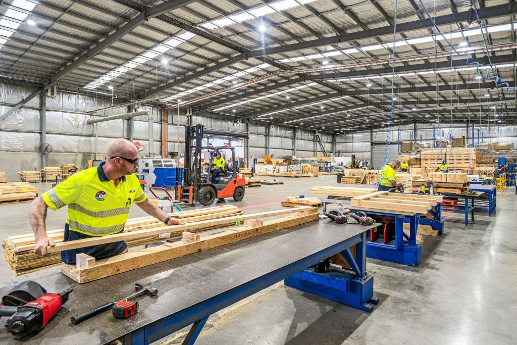 A CMTP worker feeding timber into a machine on the factory floor at the Edinburgh site in Adelaide